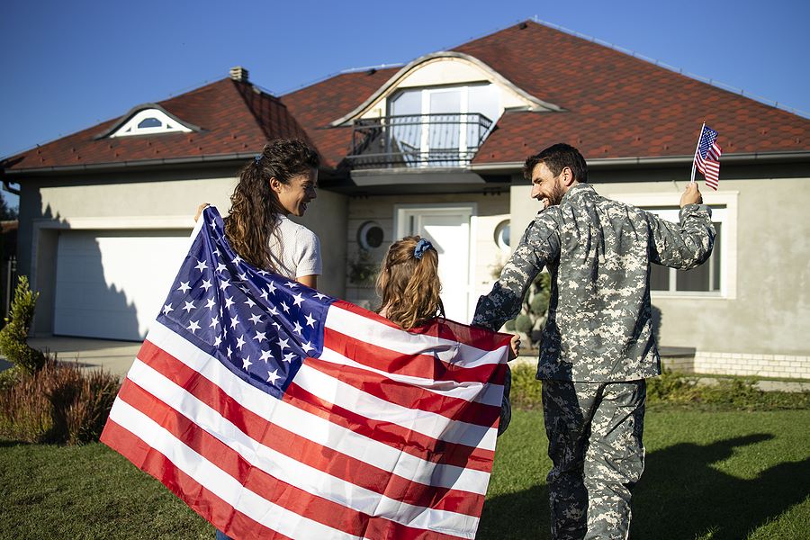 Military family in front of new home holding the american flag