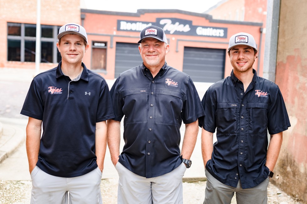 The entire Tejas Roofing & Gutters crew in front of their office building with 'Thank you for voting Tejas Roofing & Gutters Best of the Best Roofing Company & Gutter Company in Navarro County! We appreciate the continued support!' written at the bottom and the award logo on the top left